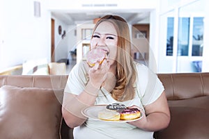 Overweight woman eats donuts