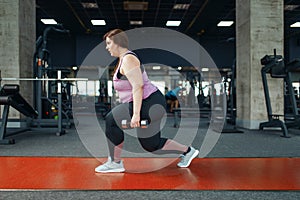 Overweight woman, exercise with dumbbells in gym