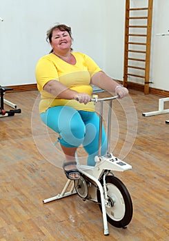 Overweight woman exercising on bike simulator