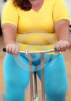 Overweight woman exercising on bike simulator