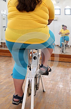 Overweight woman exercising on bike simulator