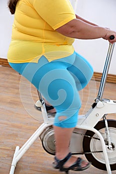 Overweight woman exercising on bike simulator