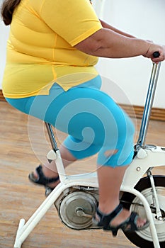 Overweight woman exercising on bike simulator