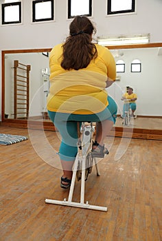 Overweight woman exercising on bike simulator