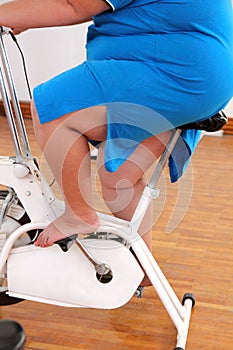 Overweight woman exercising legs on bike