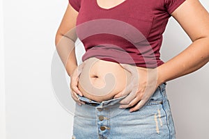 Overweight woman hand pinching excessive belly fat on gray background Healthy concept