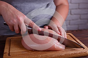 Overweight woman hands chopping up chicken breasts, close up. Di