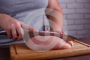 Overweight woman hands chopping up chicken breasts . Dieting, he