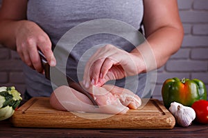 Overweight woman hands chopping up chicken breasts . Dieting, he