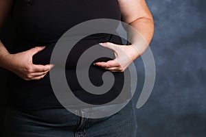 Overweight woman hands touching belly fat.