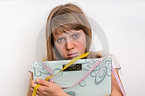Overweight woman holding digital scales with word HELP!