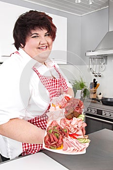 Overweight woman holding sliced ham - cooking at home