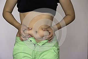 An overweight woman holds in her hand or pinches the fat folds on her stomach. Overweight concept