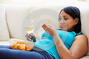 Overweight Woman At Home Eating Chips And Drinking Wine