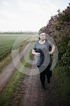 Overweight woman jogging outdoors at the open air