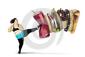 Overweight woman kicking soft drink and fast foods