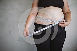Overweight woman measuring waist with measure tape