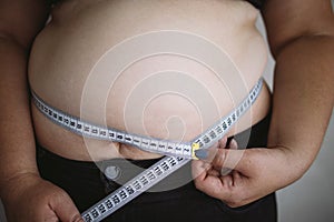 Overweight woman measuring waist with measure tape