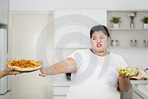 Overweight woman refusing to eat pizza