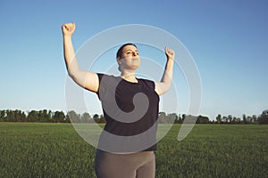 Overweight woman rising hands to the sky