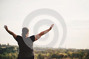 Overweight woman rising hands to the sky