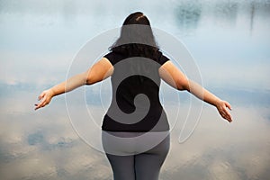 Overweight woman rising hands, view from the back