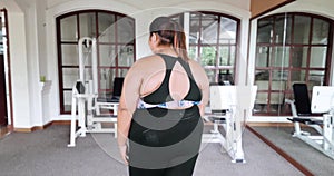 Overweight woman stands at gym and turn around