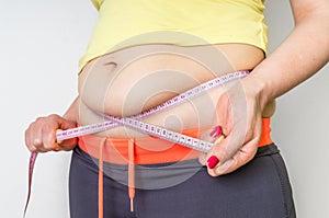 Overweight woman with tape is measuring fat on belly