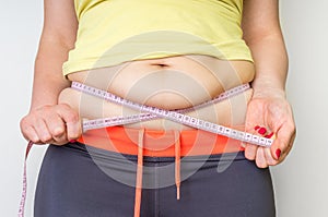 Overweight woman with tape is measuring fat on belly