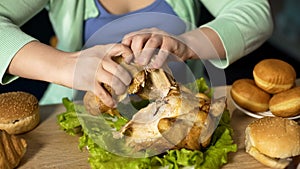 Overweight woman tearing pieces of roast chicken, overeating problem, stress