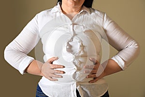 Overweight woman in tight shirt on brown background, closeup