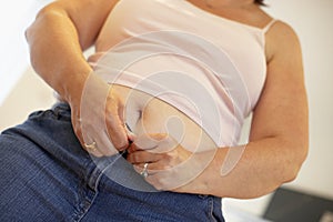 Overweight Woman Trying To Fasten Trousers photo