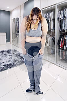 Overweight woman trying to wear tight jeans