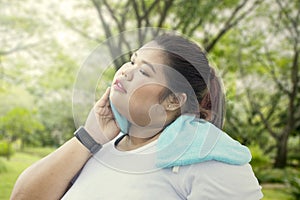 Overweight woman wiping her sweat at the park