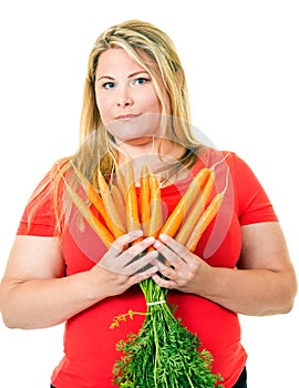 Overweight young blond woman with fresh carrots