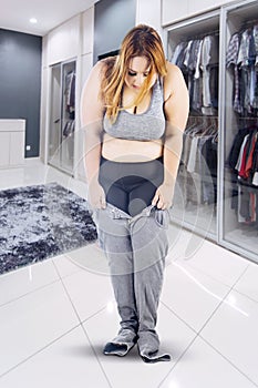 Overweight young woman trying to wear tight jeans