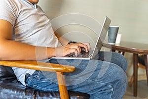 Overweighted human sitting armchair and typing laptop at coffee table