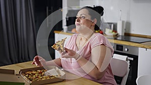 Overweighted woman eats with great pleasure, woman eats pizza, rolls eyes