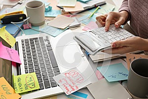 Overwhelmed woman working at messy office desk, closeup