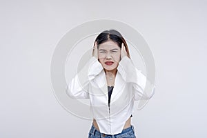 An overwhelmed young woman covering her ears in distress with eyes closed. Isolated on a white background