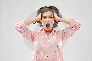 Overwhelmed young woman in pajama holding to head