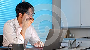 Overwork Concept The employee sitting in the office and yawning at his desk