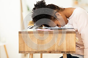 Overworked African Girl Resting Head On Desk Sitting Indoor