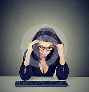 Overworked bored woman sitting at desk in front of her computer looking down