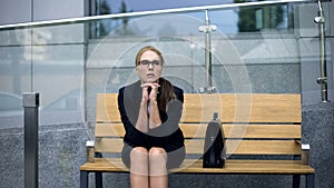 Overworked business woman sitting on bench near office, exhausting working day