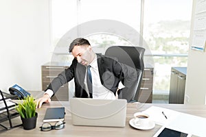 Overworked Businessman With Backache In Office