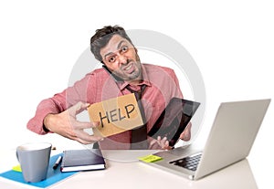 Overworked businessman busy at office desk working on computer mobile phone and digital tablet asking for help