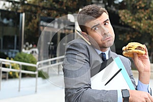 Overworked businessman eating fast food on the go