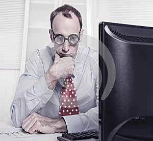 Overworked businessman with glasses staring into space at desk