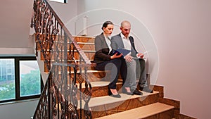 Overworked businessman reading raport on stairs